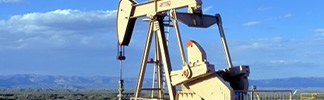 An oil drilling rig with blue skies and mountains in the background.