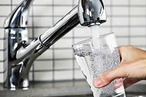 A glass of water being filled by a faucet